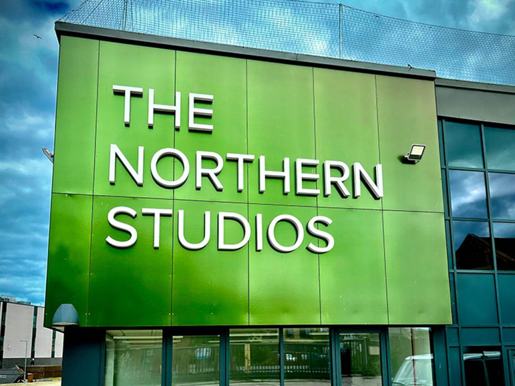 Large outdoor green industrial signage on the side of a warehouse